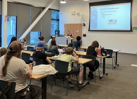 Personal safety workshop where people sitting at tables listen to a speaker at a podium.
