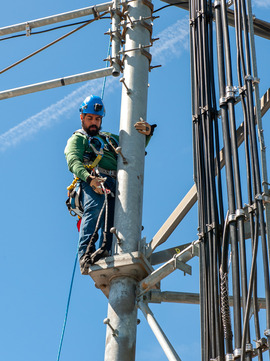 BTS technician Josue Castaneda climbs a radio tower at Goat Mountain using ropes and harness.