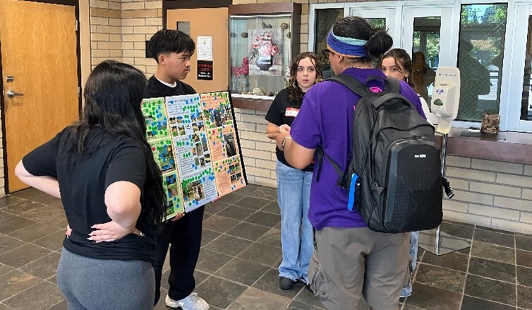 Youth in Lents hold a poster with ideas for improving Lincoln Park and chat with a neighbor outside.