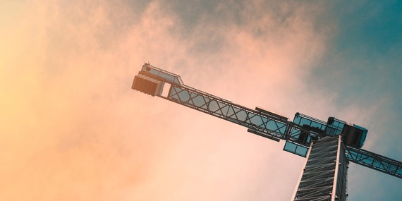 Construction crane framed against salmon-colored sky
