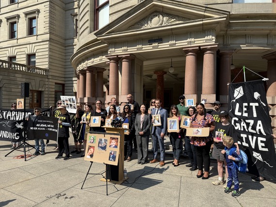 Group of people gathered on the steps of City Hall, with a sign that says Let Gaza Live, and pictures of family members affected by war