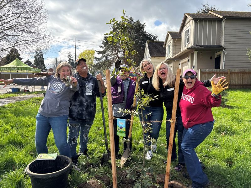 PPR_ group of people smiling behind a small planted tree 