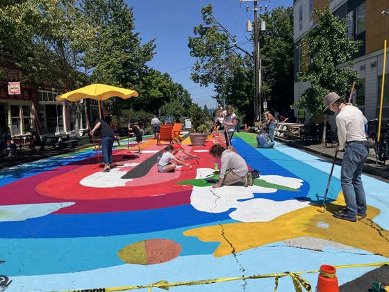People putting a fresh coat of paint on the street at Concordia Commons