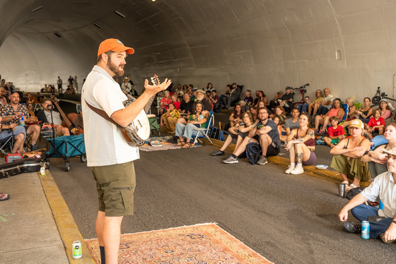 A man plays banjo to a crowd in the rocky butte tunnel