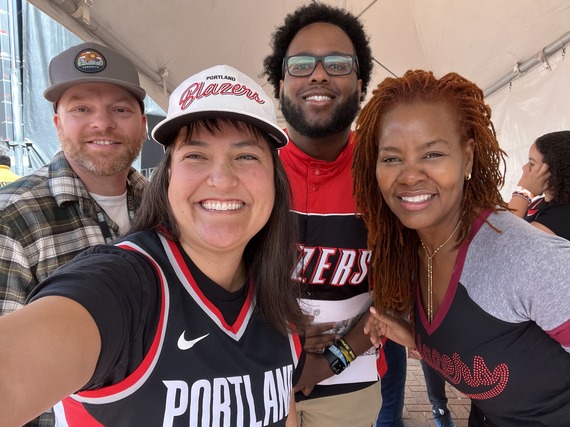Four people smiling at the camera, wearing Portland Trailblazers gear