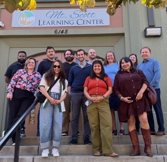 Group of ten people on steps outside of Mt. Scott Learning Center, looking at the camera and smiling