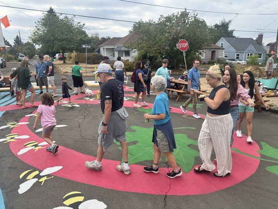 People parade along the painted spirals of the Roseway Plaza mural