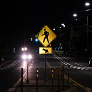 Dark street or road with a pedestrian crossing sign lit up