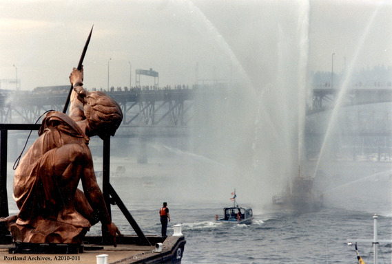 Portlandia photo from 1985 as the statue is barged down the Willamette River and a fireboat sprays water