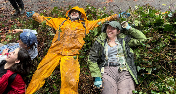 Two happy volunteers take a break by sprawling on a pile of ivy pulled from a park.