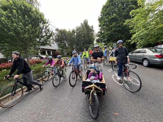 More than 15 kids and adults ride their bikes to school along a neighborhood greenway.