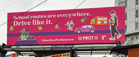 A pink billboard of a car on a street with kids walking and rolling with text, “School routes are everywhere. Drive like it.”