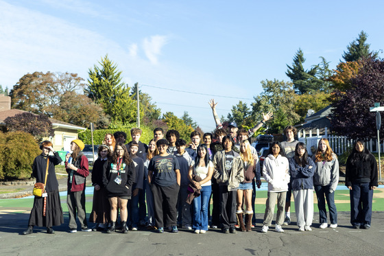 A class of high school students take a group picture with their teacher at a painted street intersection.