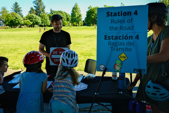 An adult teaches elementary school kids at a bike fair the rules of the road. 