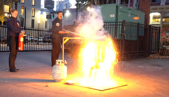 Two firefighters observe a deep fryer fire after placing a turkey into it