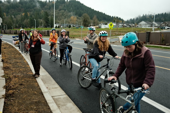 About 10 adults get ready to ride their bikes in the bike lane in a suburban neihgborhood.