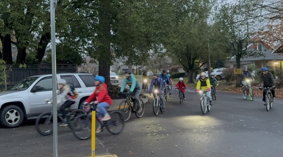group of colorfully dressed bicyclists riding along a curve on a street