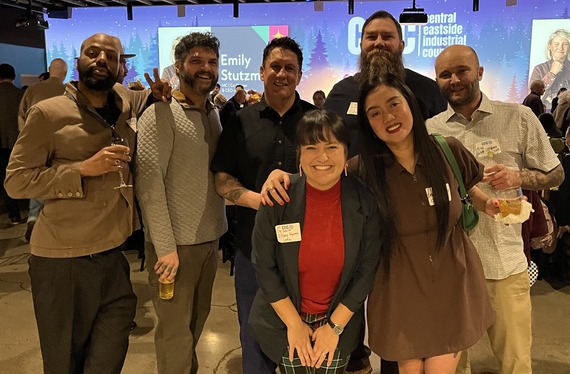Group of seven people smiling at camera, in front of slide reading "central eastside industrial council"