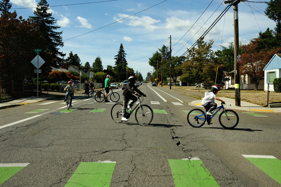A group of elementary school students on bikes making a left turn at an intersection.