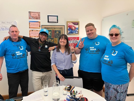 five people smiling at camera, three wearing bright blue "Drivers Union: Our Voice for Fairness" t-shirts
