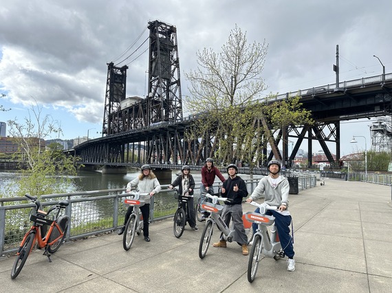 High school students sit on BIKETOWN bikes with the Steel Bridge in the background for ambassador program