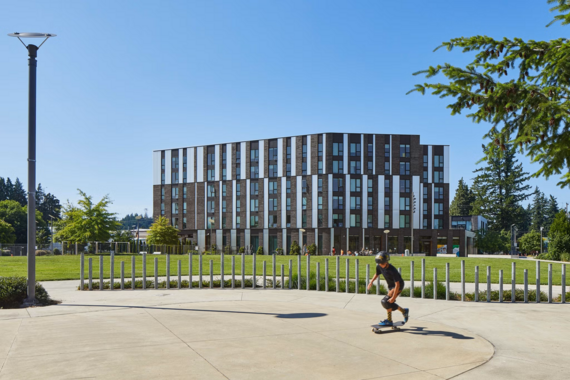 Kid riding skateboard in front of new housing building