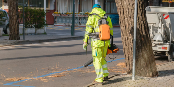worker in reflective clothing using an electric leaf blower