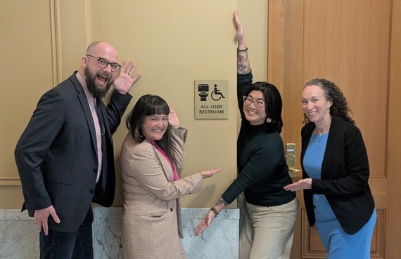 Council President Dunphy, Councilor Koyama Lane, policy advisor Aubri Qian, and Councilor Pirtle-Guiney smiling around all-user restroom sign