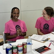 Two people in pink t-shirts smile while doing City Elections office voter education