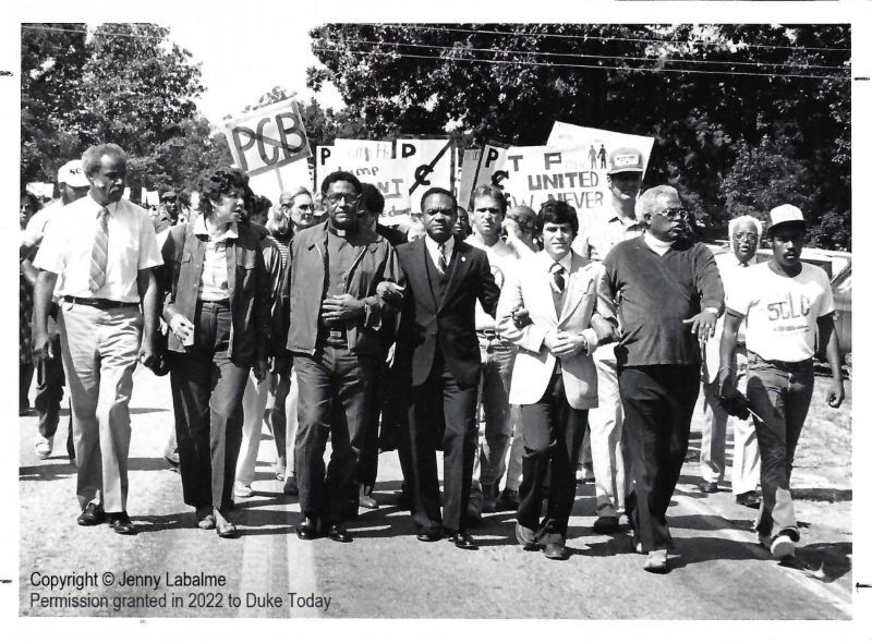 PPR - Black and white photo of a group of people, in locked arms, protesting in the middle of a road
