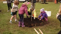 PPR - Woman with three children spread mulch around a tree