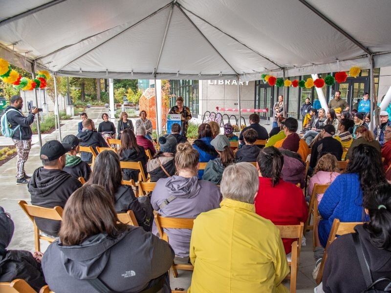PPR - Group of people looking toward someone speaking under a big tent
