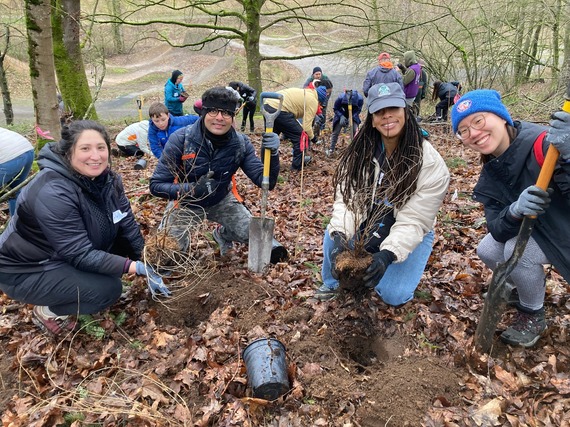 A group of smiling people dressed for outdoor planting and trail maintenance