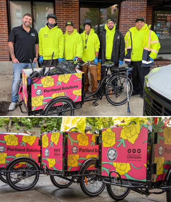 Basic street cleaning crew with Central City Concern smiles at the camera with bike powered carts painted bright pink and yellow flowers.
