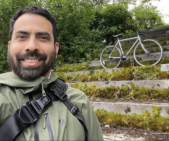 Ernesto, a Sunday Parkways volunteer, poses for a selfie with his bike in the background.