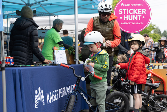A family of three enjoying vegetable samples from a Kaiser Permanente booth during a Portland Sunday Parkways event.