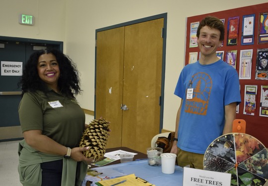 PPR - two people standing around a table with a big pine cone 