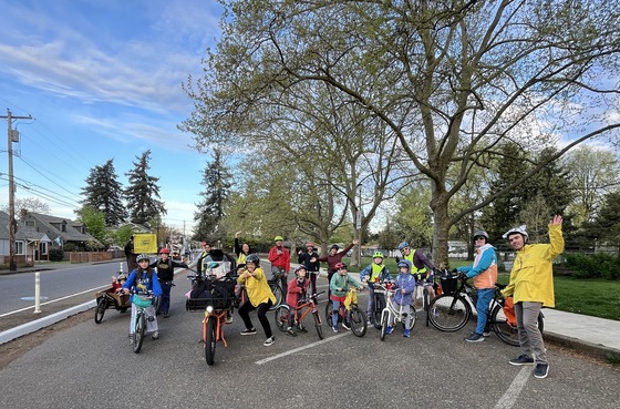 A group of about two dozen kids and families stop at a park in the middle on their bike ride to school.