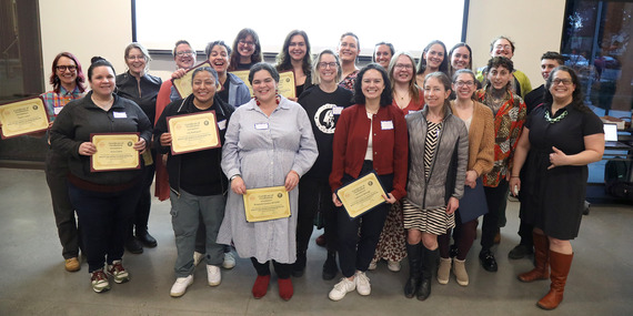 A large group of smiling people holding Rose City Self Defense volunteer certificates
