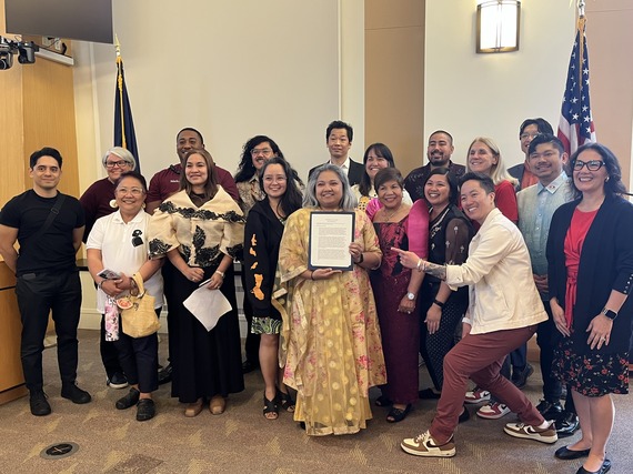 Group of people smiling at camera, holding a proclamation declaring May as AANHPI Month