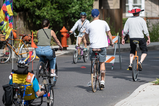 Sunday Parkways event participants riding bikes and a unicycle on a car-free street. 