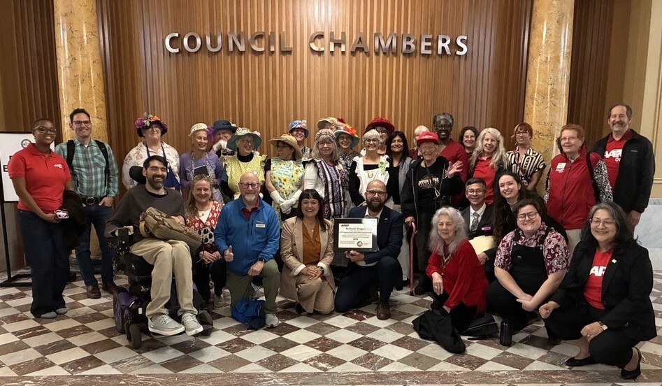 Large group of people in front of Council Chambers wood wall, Councilors Dunphy and Koyama Lane holding AARP Liveable Community Plaque