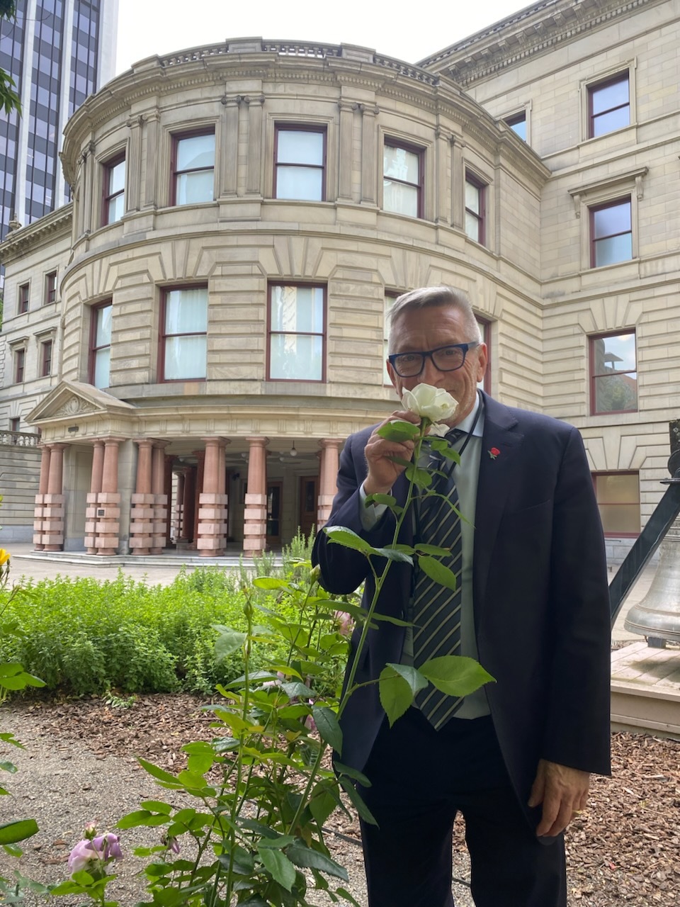 Councilor Ryan smelling a rose growing outside of Portland City Hall.