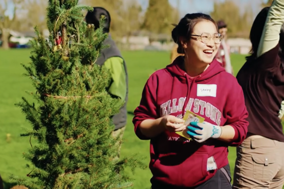 A young adult smiles while working in a city park planting trees