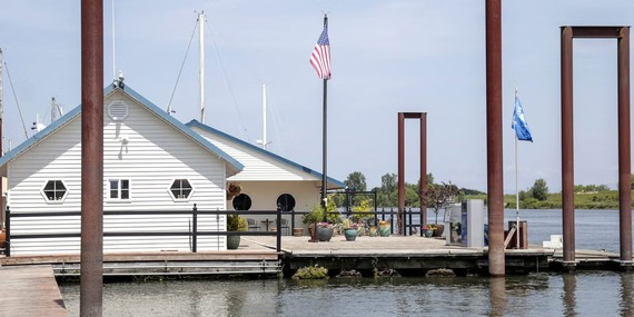 A houseboat on the river; floating home shows a big deck and white house