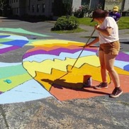 A person paints a street colorfully for a placemaking project - street art - street painting