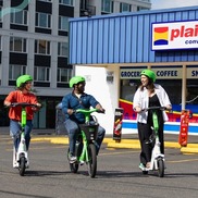 Three people ride Lime scooters in front of a Plaid Pantry for the free helmet promotion with PBOT
