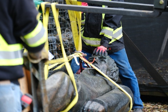 Abraham Lincoln monument is on the ground with people in safety gear moving it
