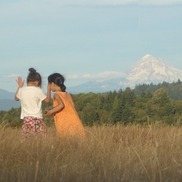Two children play in the tall grass at Powell Butte