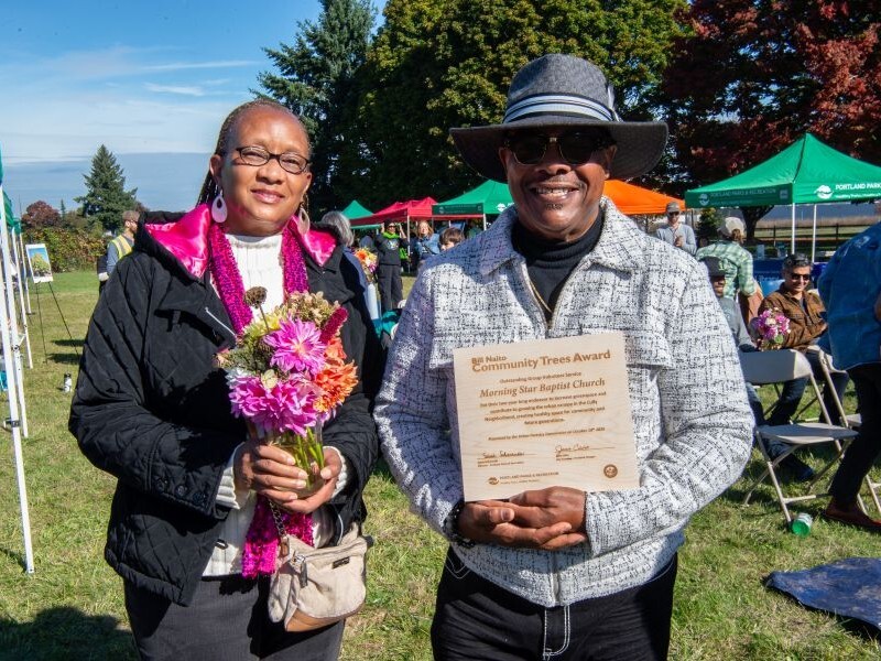 Man holding wooden plaque and woman holding bouquet of flowers 